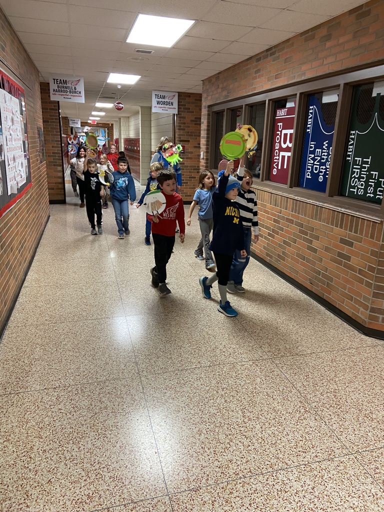 students parading down the hallway holding up paper plates decorated like baloons.