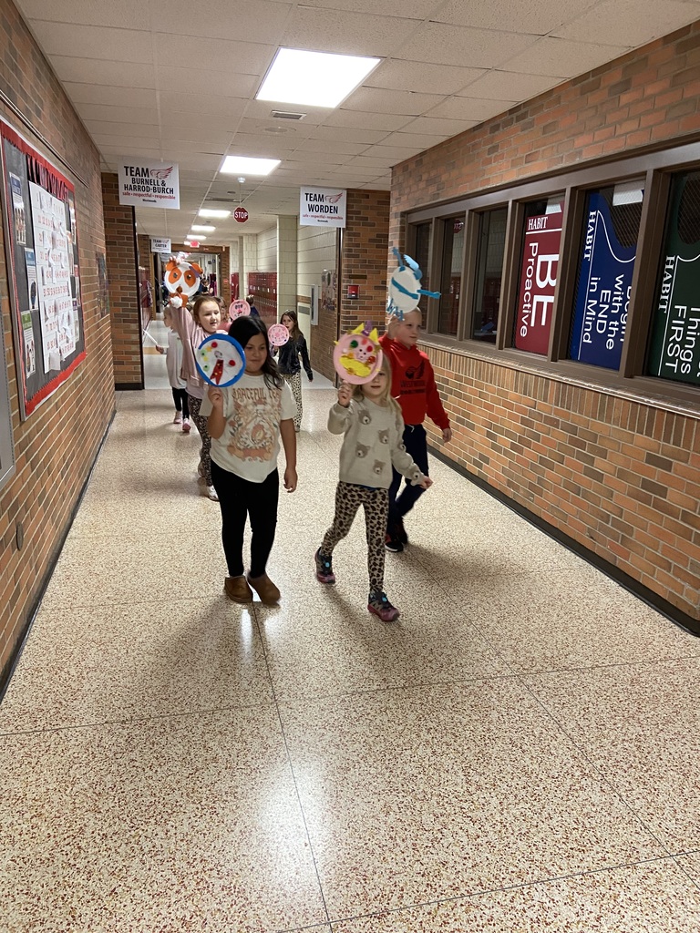 students walking down a hall wall holding up paper plates decorated like balloons