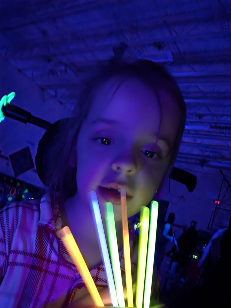 student holding glow sticks smiling