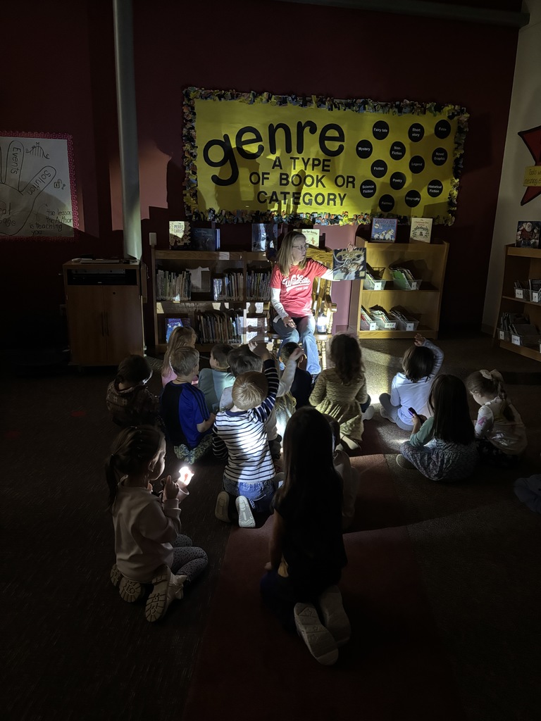 librarian reading a book in the dark with kids shining their flashlights on the book