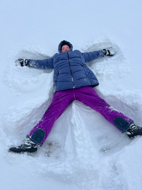 student laying in the snow making a snow angel