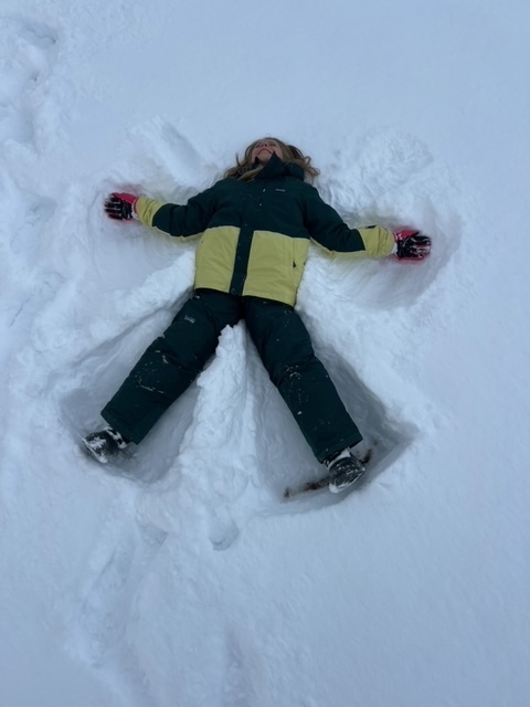 student laying in the snow making a snow angel