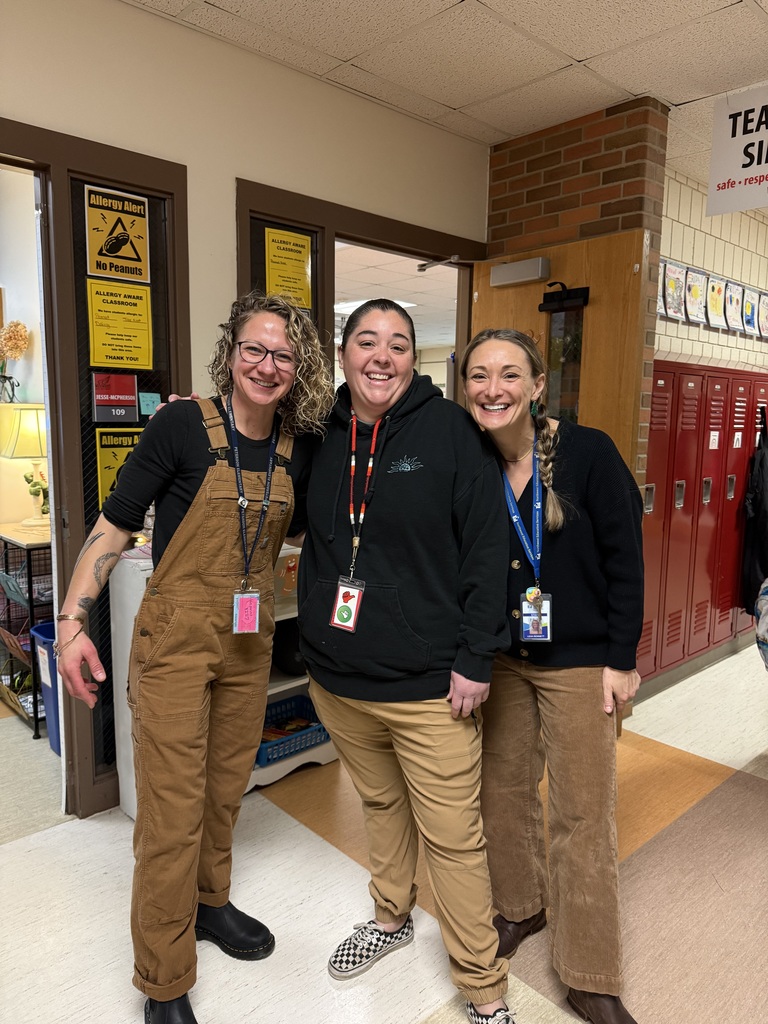 3 teachers wearing brown and black standing together and smiling at the camera