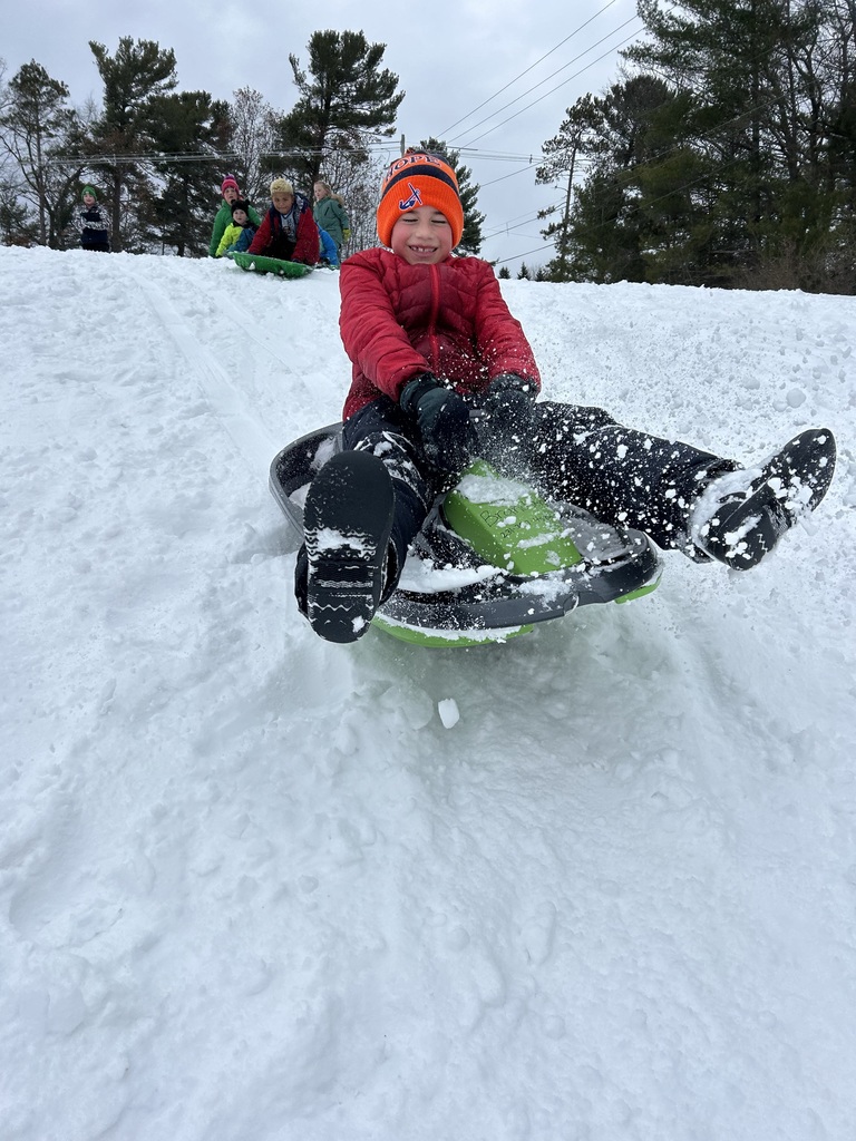 One second grade boy sledding down the hill.