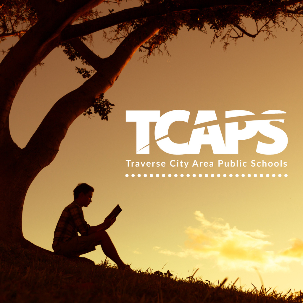 Warm-toned photo with a silhouette of a person reading under a large tree and the TCAPS school logo