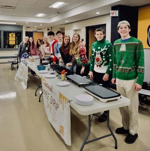 Students in the hallway serving pancakes