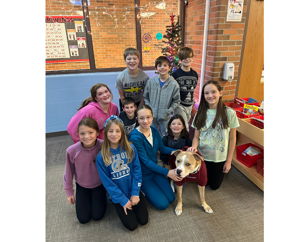 Students standing in front of a tree smiling, with Wilbur our therapy dog in the center