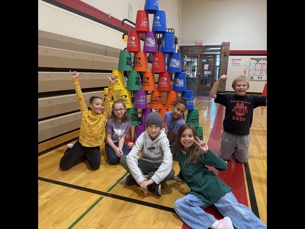 Third grade students sitting by stacked cups