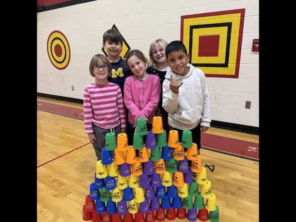 first grade students standing by stacked cups