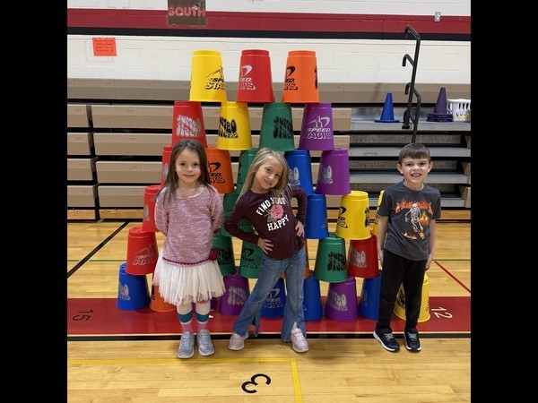 Kindergarten students standing by stacked cups