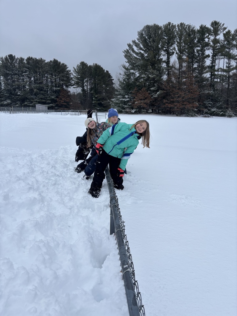 Big snow drift with kids on both sides of the fence.