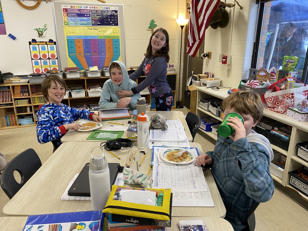 students sitting at their desk, eating pancakes and smiling