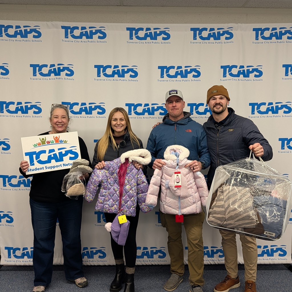 Staff from The Mitten Group and TCAPS Student Support Network smiling with winter gear donation.