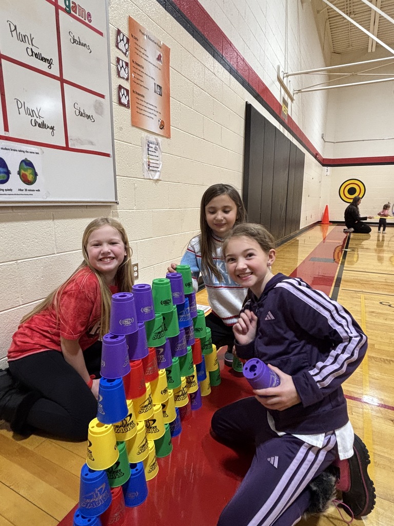 3 girls kneeling by a tower of cups