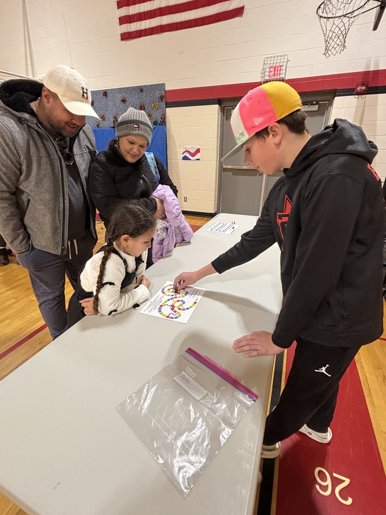 a middle school studnet showing a family how to play a game on a gameboard