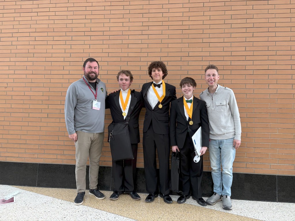 Two instructors and three students in tuxedos with All-State medals pose together against a brick wall.