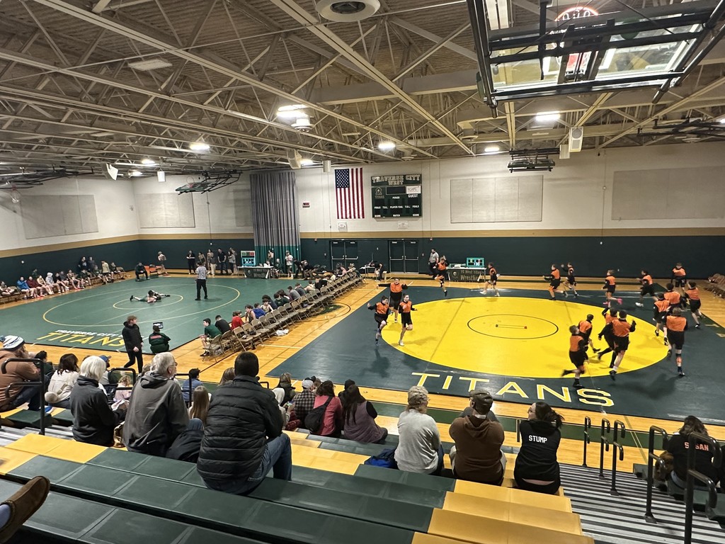 Wrestling match with parents in bleachers and athletes warming up and competing