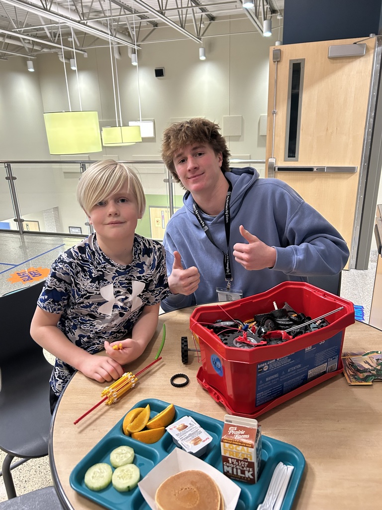 Volunteer from Big Brothers, Big Sisters Organization sitting at a table with a student building a toy