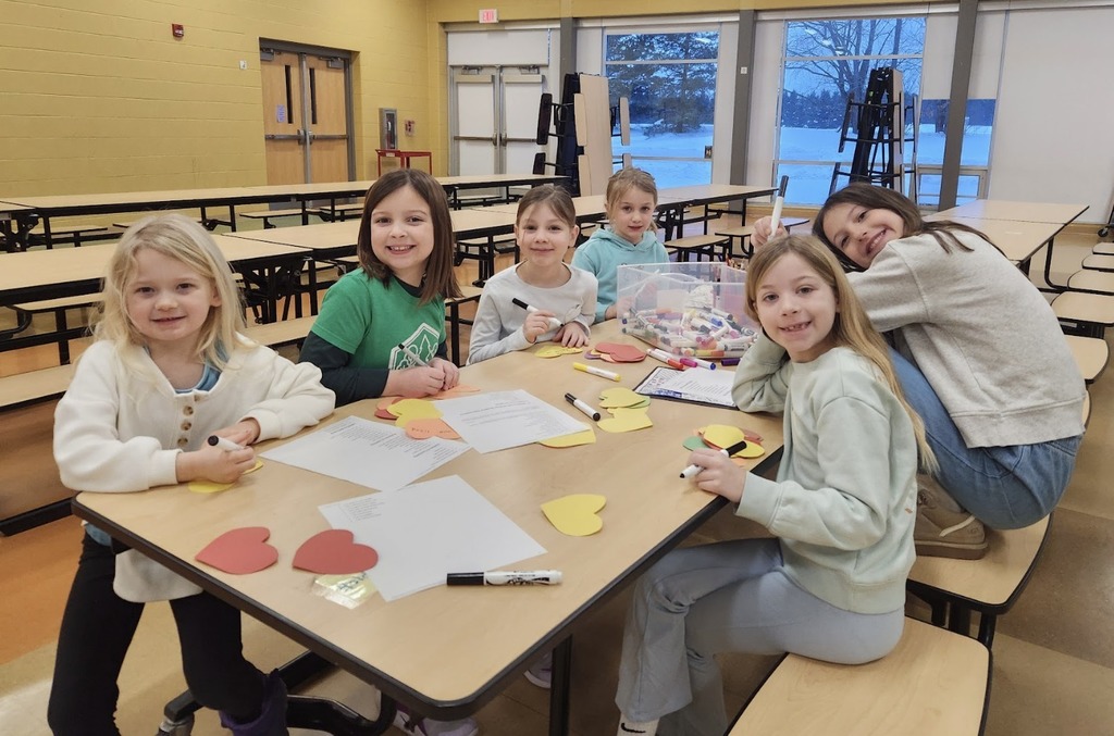 Students sitting at a table making paper hearts