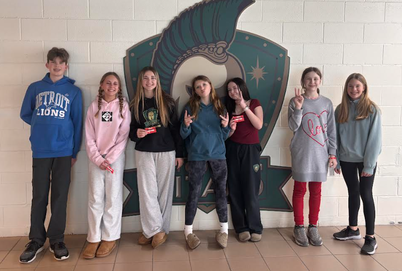 Group of 7 registration volunteers standing in front of the Titan Logo