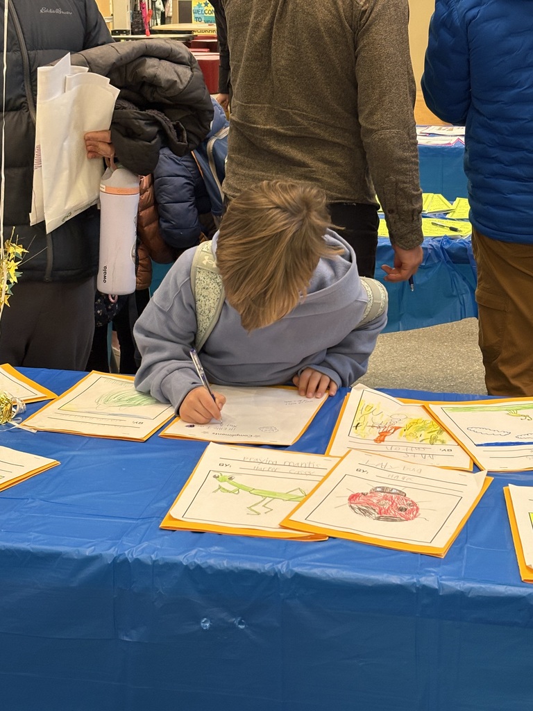 One Eastern male student is bent over a piece of writing, holding a pencil writing a comment on the page.