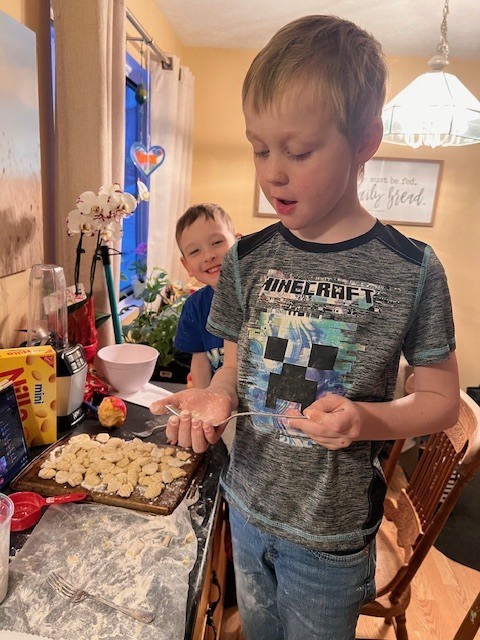 A boy using a fork to put some marks in the gnocchi