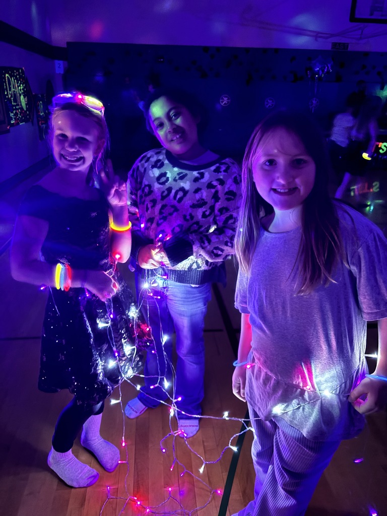 3 girls with lights strung around them in a dark room