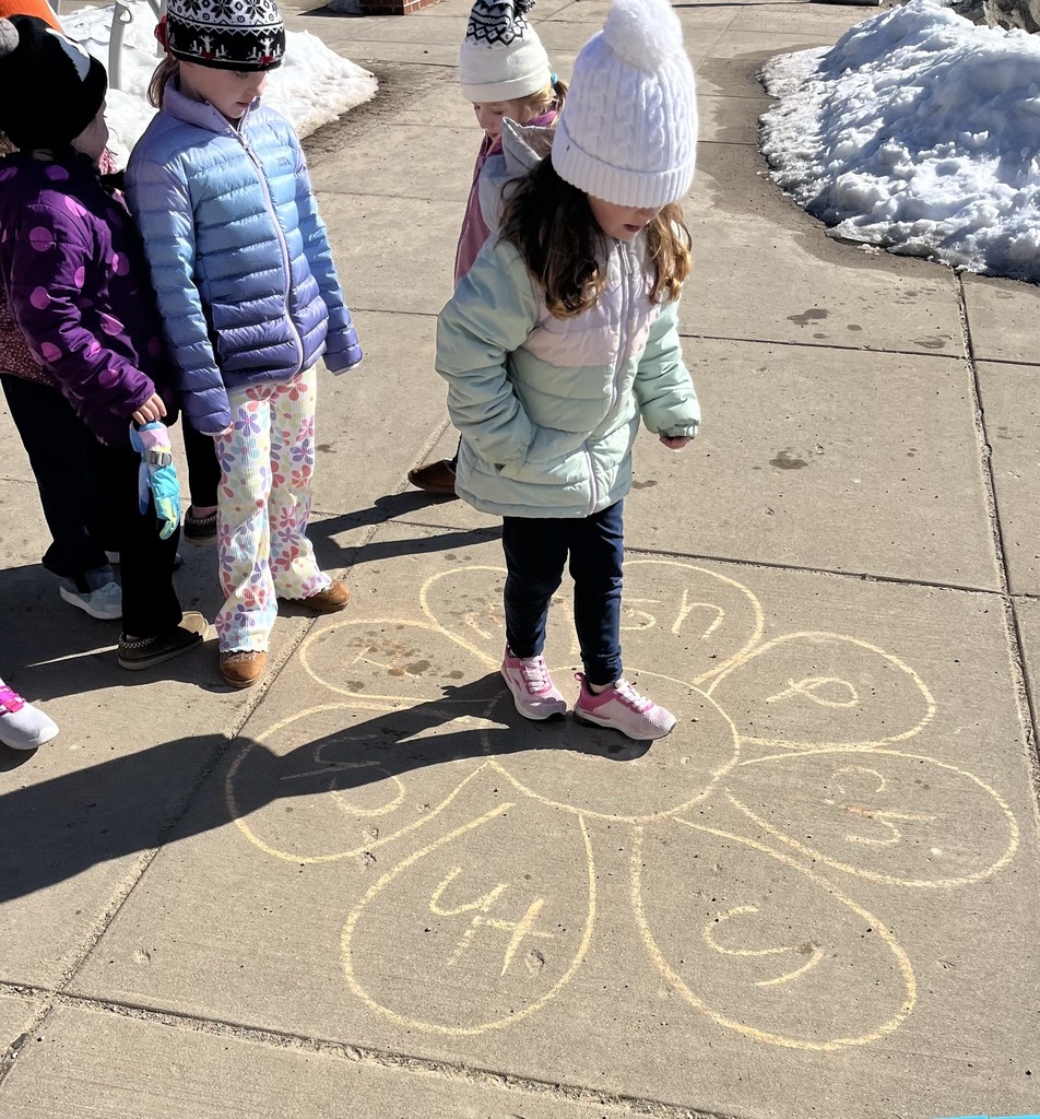 students outside standing on the sidewalk with chalk drawings