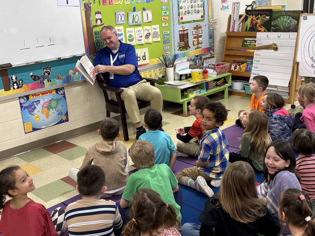 Teacher reading a book to a group of students.