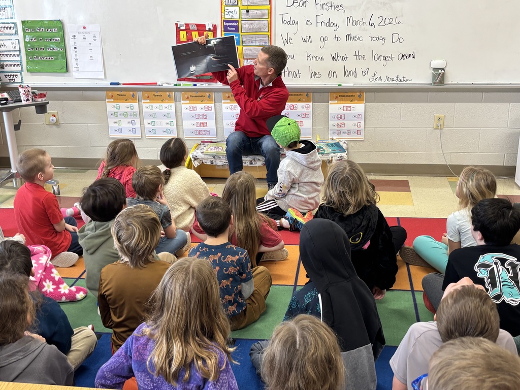 Teacher reading a book to a group of students.