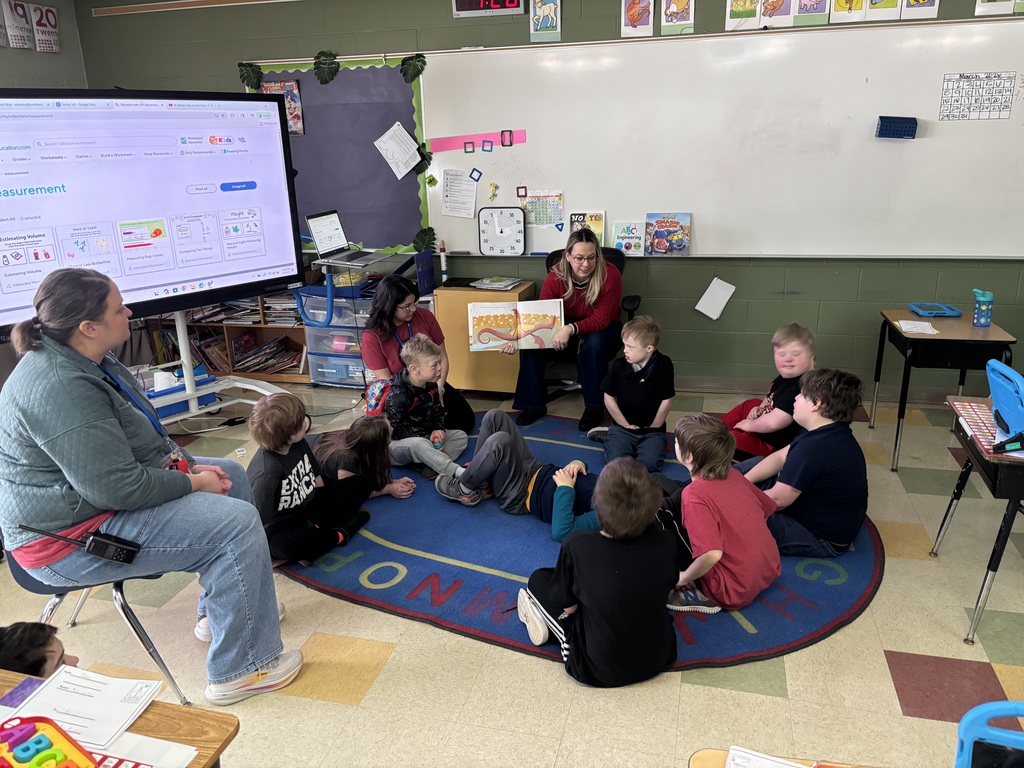 Teacher reading a book to a group of students.