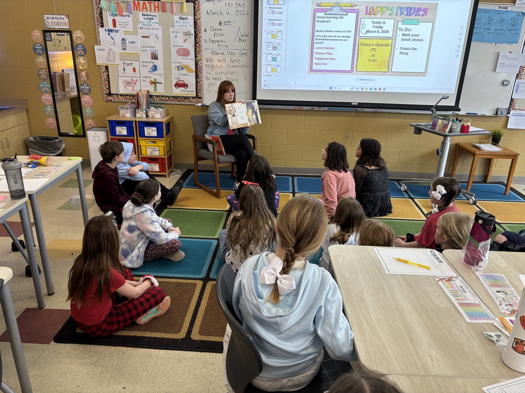 Teacher reading a book to a group of students.