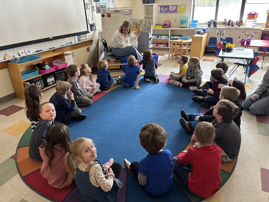 Teacher reading a book to a group of students.