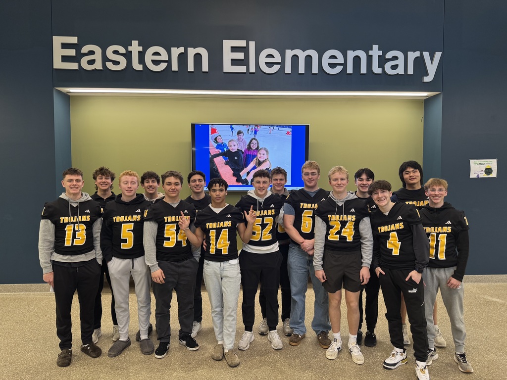 A group of Traverse City Central football players standing in a staggered line in the Eastern lobby wearing their football jerseys