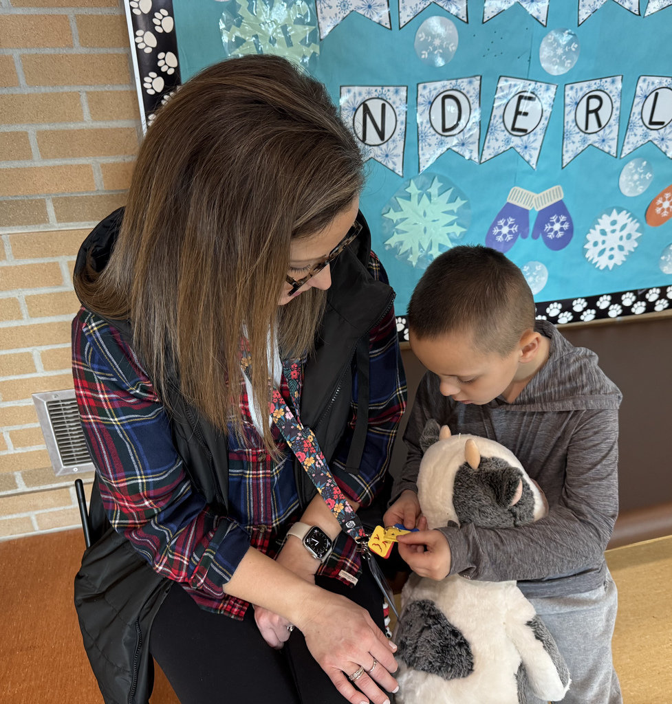 School Social Worker and a student siting together on the floor looking at her badge
