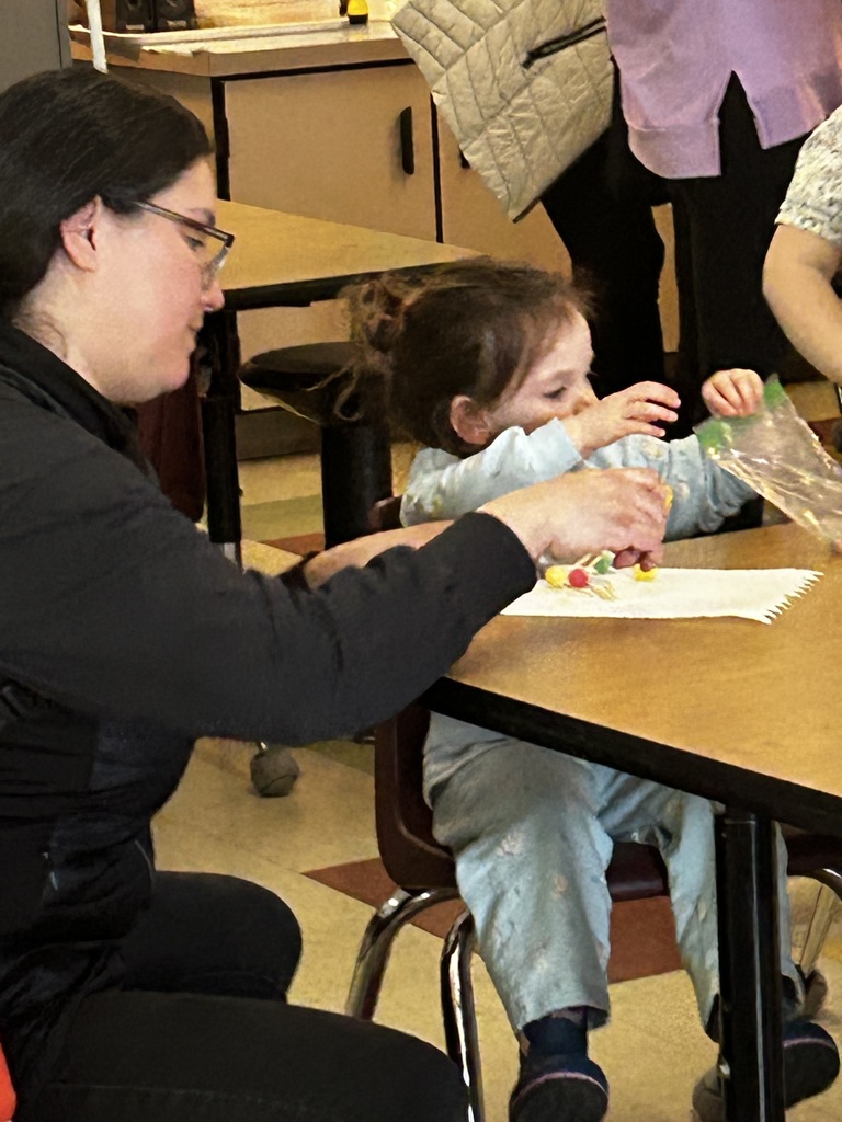 A mom building something out of toothpicks and gum drops with her daughter.  