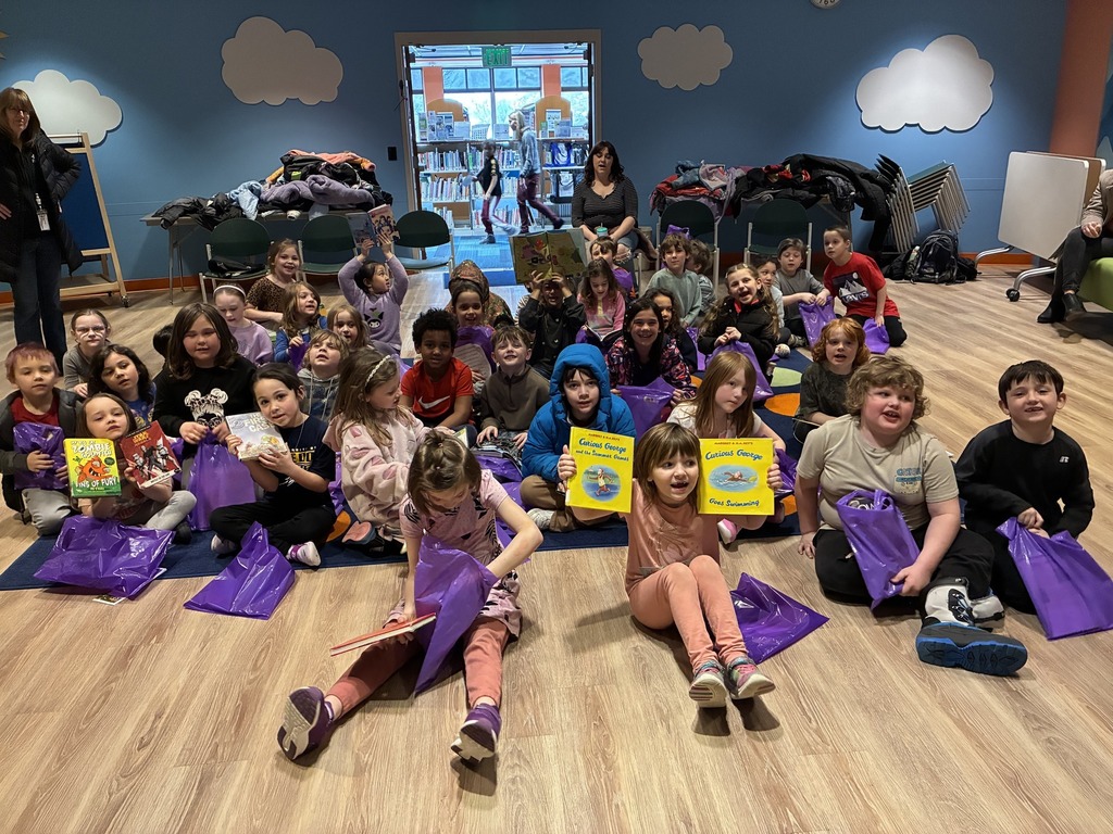 students sitting on the floor holding books up.