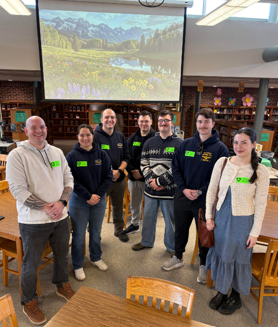 Coast Guard members standing in front of a projected meadow screen. 