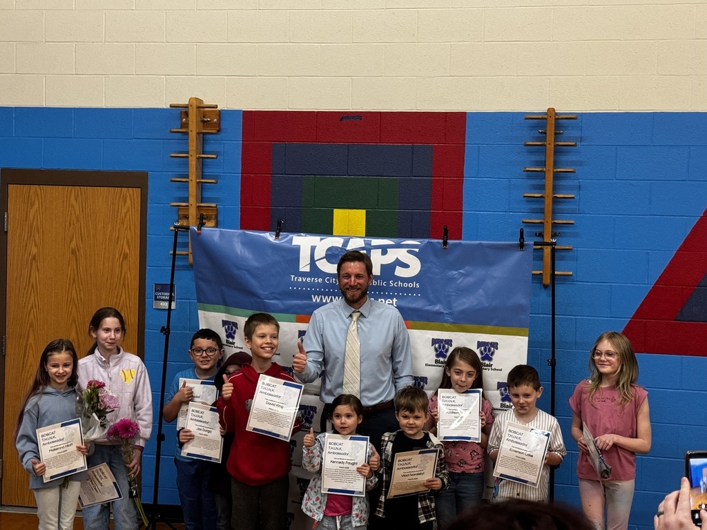 Principal and students standing in a row holding their certicates.