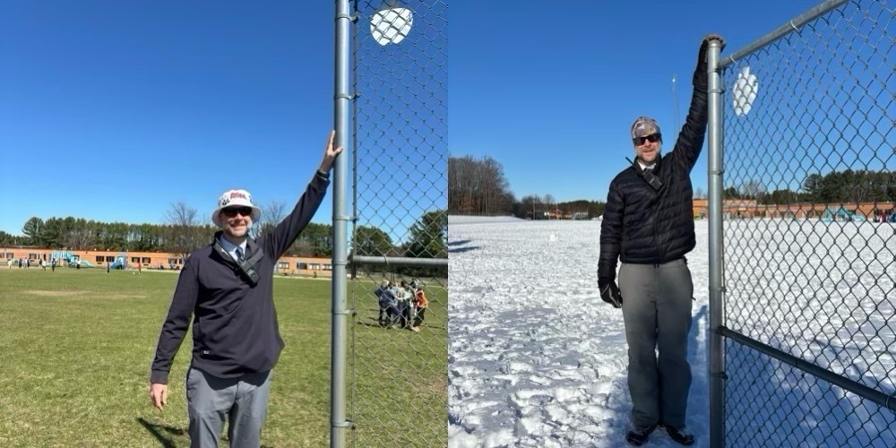 Two men stand behind a fence; one has his hand on the top, both wear winter attire. The background shows a grassy field and a snowy landscape.