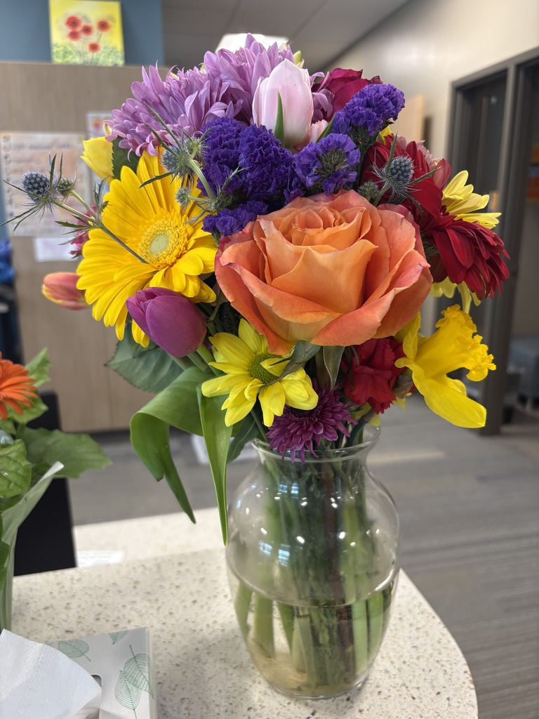 A vase full of multi-colored fresh flowers on a desk top