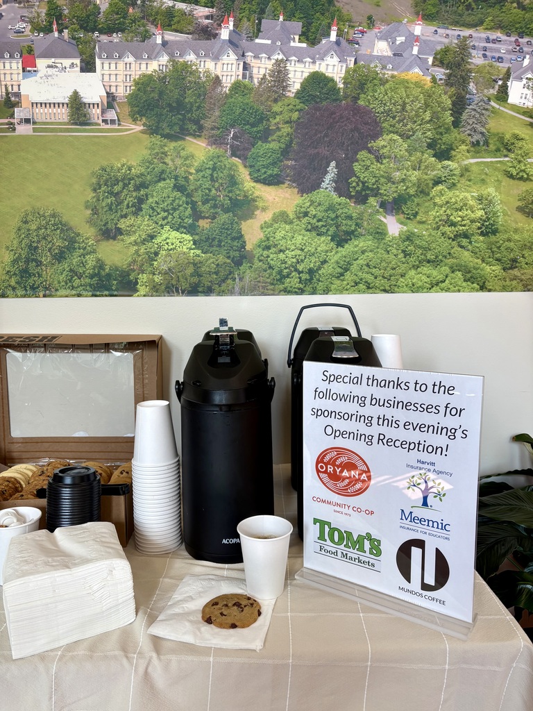 Display table with cookies, cups, napkins, and a black coffee machine. A sign reads, "Special thanks to the following businesses for sponsoring this evening's Opening Reception!"