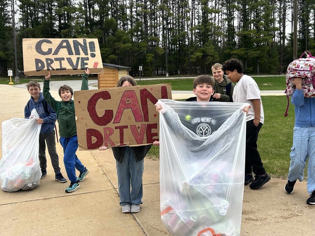 Group of children with homemade signs and plastic bags with collected items in a park area.