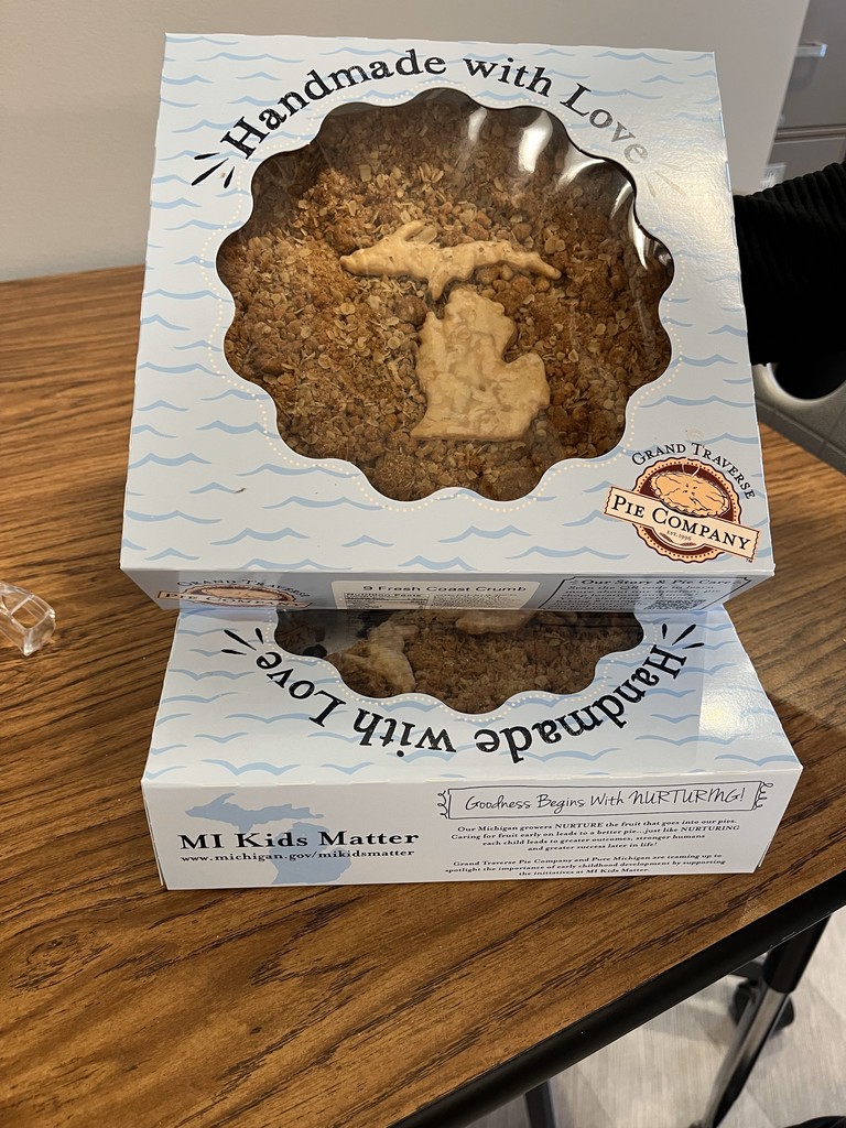 Two boxes of pie stacked on a wooden table. One box has the word "Handmade with Love" and a Michigan outline.