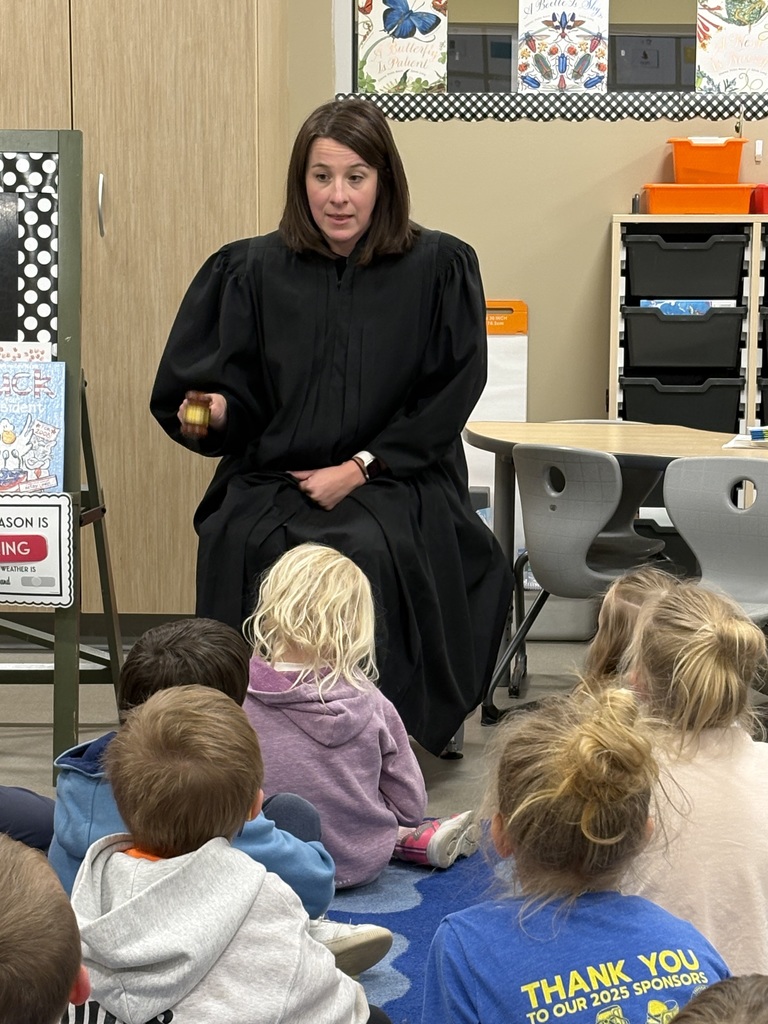 Probate Judge Jennifer Whitten addresses a classroom of kindergarteners holding a gavel, sitting next to a table.