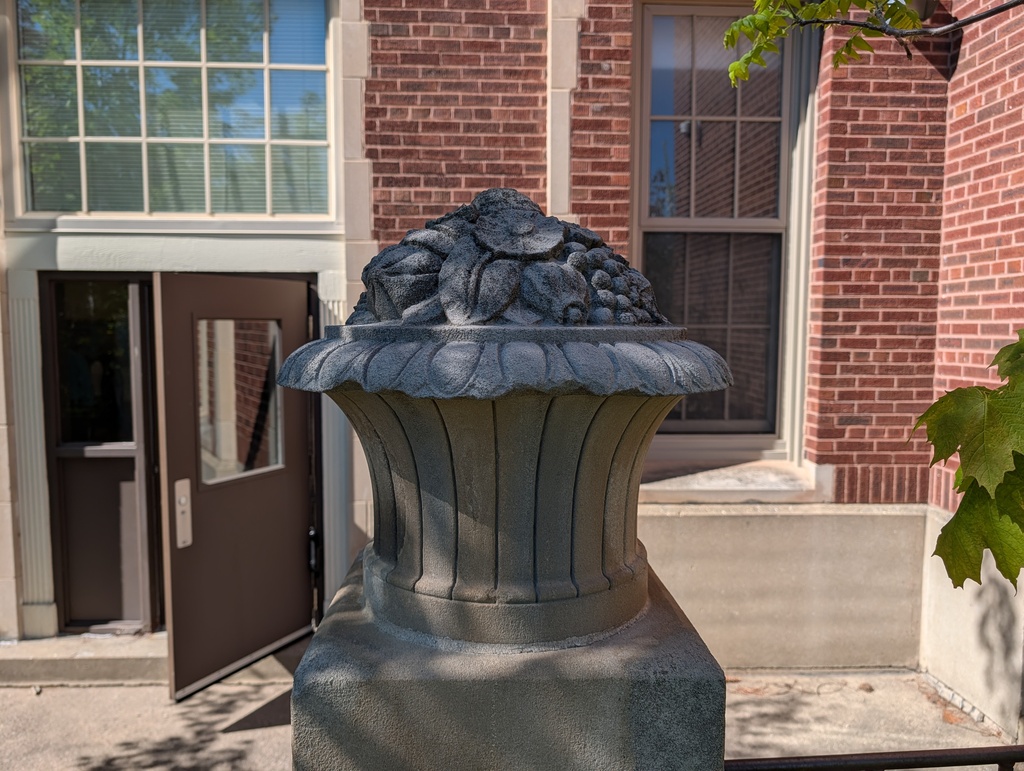 An entrance with a brick wall and windows. A large gray stone base in front of the doorway.