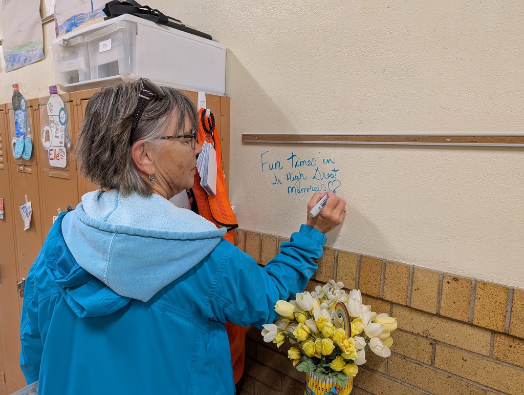 A person wearing a blue hoodie writes on a wall with a marker. 