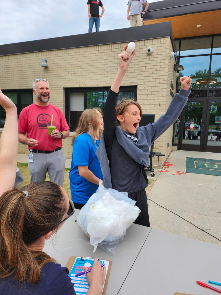 A group of people on a sidewalk. One person throws a snowball. Another person records on a clipboard.