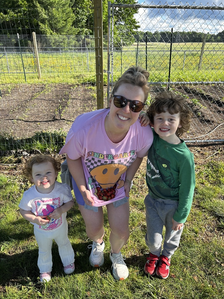 A woman and two children stand in a garden, smiling and posing for a photo.