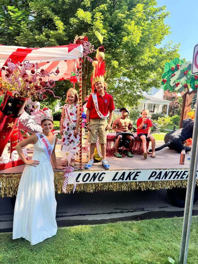 Decorated float with people. A woman in white stands on the front. A banner reads "Long Lake Panther".